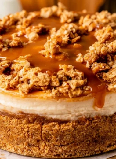 Delicious apple crumble cheesecake topped with cinnamon and crumble on a plate