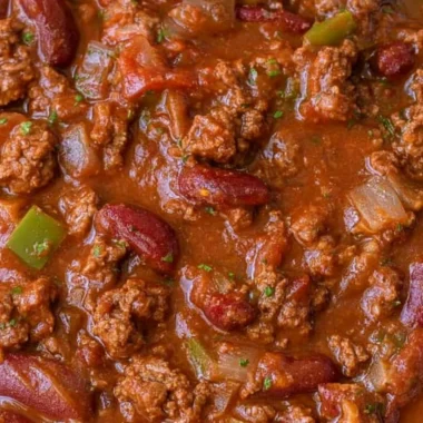 Cozy easy chili recipe, a warm bowl of homemade chili topped with fresh herbs.