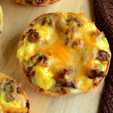 Cozy English muffin breakfast pizza topped with eggs, cheese, and veggies