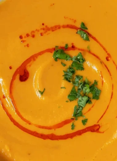 Bowl of cozy sweet potato soup garnished with herbs and spices
