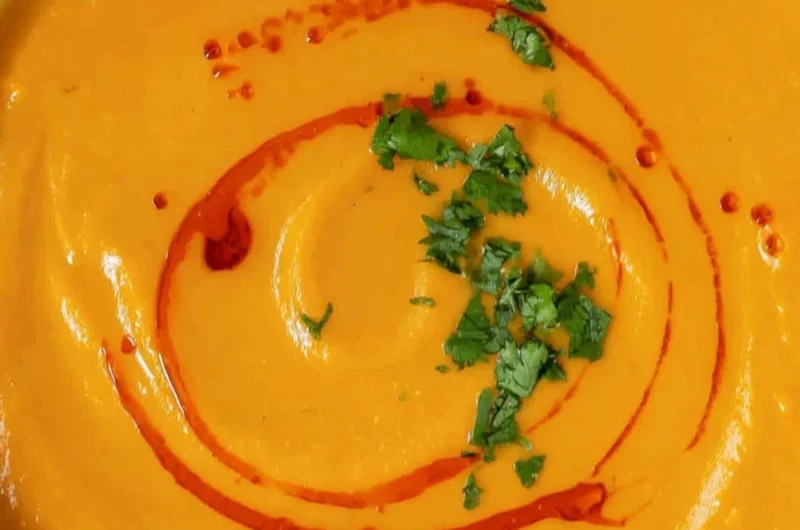 Bowl of cozy sweet potato soup garnished with herbs and spices