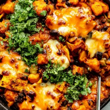 Cozy butternut squash and black bean enchilada skillet topped with cheese and herbs