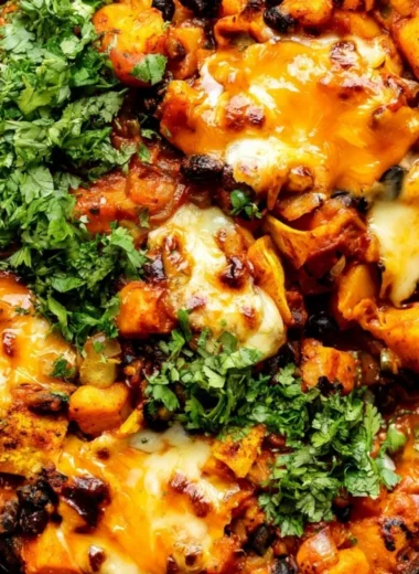 Cozy butternut squash and black bean enchilada skillet topped with cheese and herbs