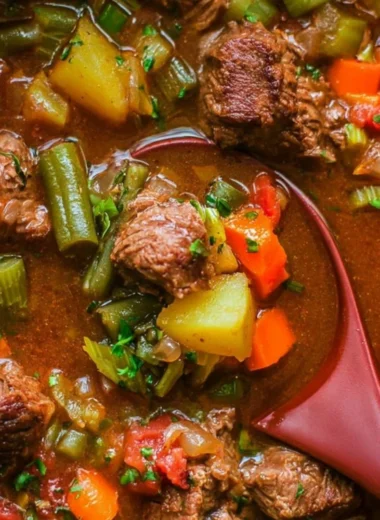 A bowl of cozy vegetable beef soup with colorful vegetables and tender beef pieces.