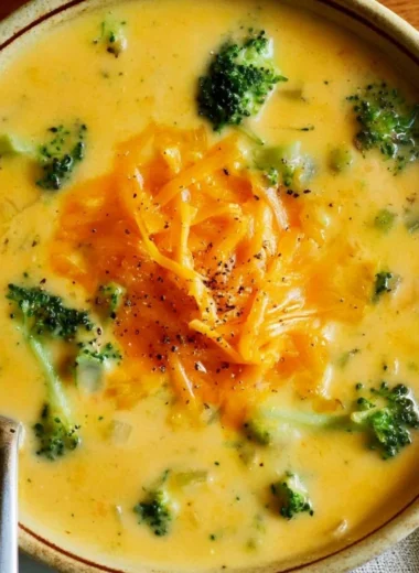 Creamy broccoli cheddar soup served in a bowl with fresh broccoli florets