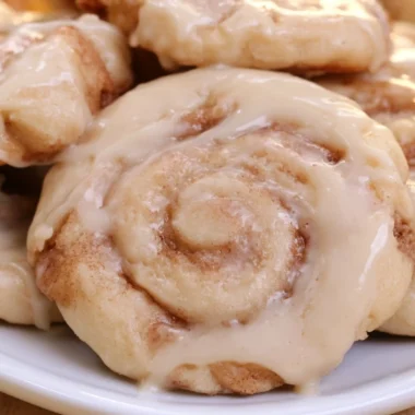 Delicious soft cinnamon roll cookies on a plate with icing