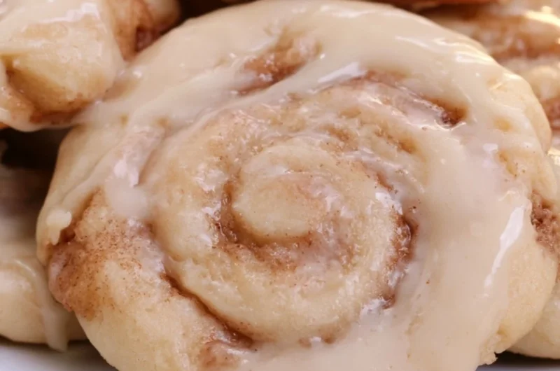 Delicious soft cinnamon roll cookies on a plate with icing